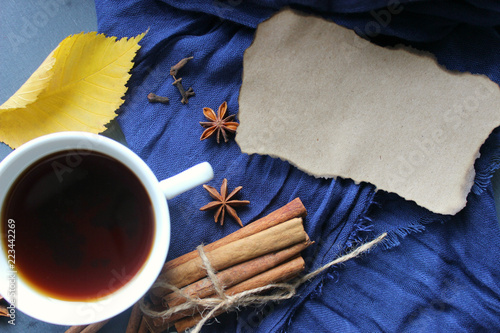 Autumn still-life. A Cup of hot tea yellow autumn leaf and spices, cinnamon sticks, anise, cloves on a blue scarf background. Warm warming drink, comfort, relaxation, relaxing drink.Tea, coffee with s photo