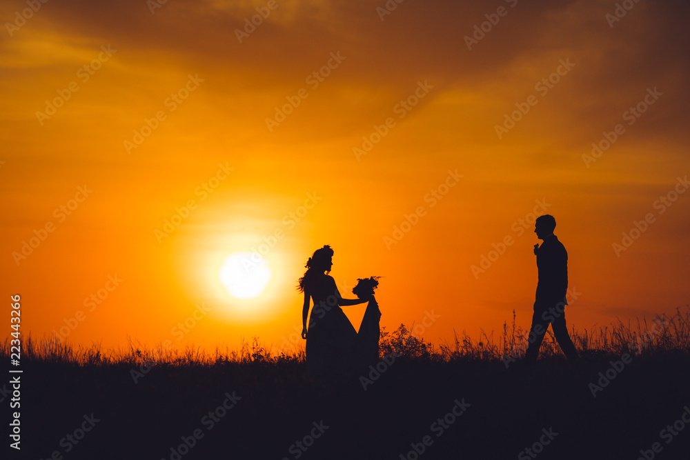 Silhouette of bride and groom at sunset.