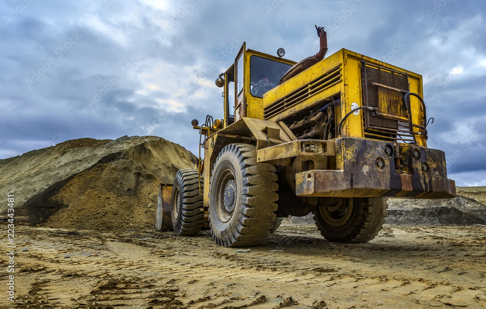 excavator working on sand dunes, cloudy day, beautiful storm clouds, bottom view, point of view