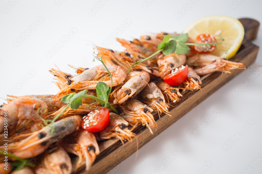 Lots of shrimps on the wooden board with lemon Lots of shrimps on the wooden board with lemon