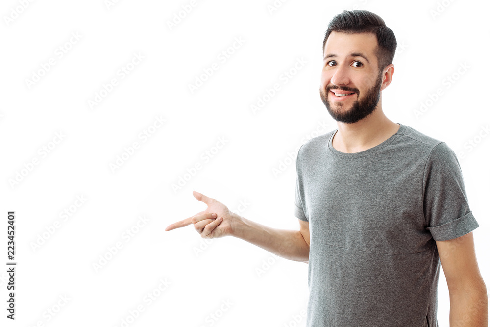 Young cheerful bearded man pointing finger at empty space on background isolated on white background Young cheerful bearded man pointing finger at empty space on background isolated on white background