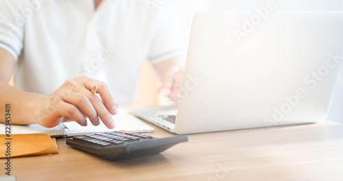 close up accountant business man writing cost estimate and pressing on calculator at office desk concept photo
