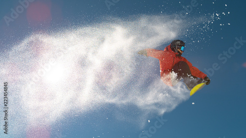Fotografi SLOW MOTION: Snowboarder jumping big air, snowflakes flying behind him in winter