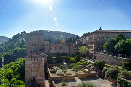 Noon day sunlight streaming over ancient Moorish European palace complex, gardens, and hills.