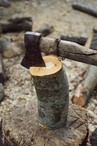 The old ax for cutting firewood sticks out in the old tree stump. A sharp ax was stuck in a round old wooden stump