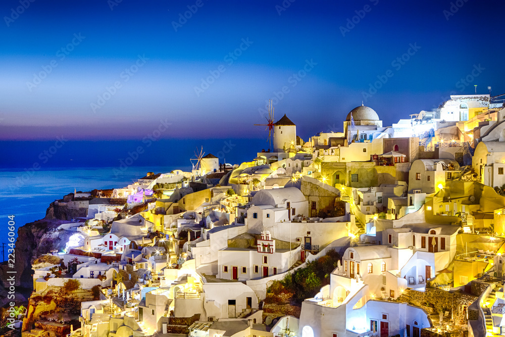 New Destinations Concepts. Sunset at Santorini Island in Greece. Image Taken in Oia Village At Dusk. Amazing Sunset with White Houses and Windmills in Frame.