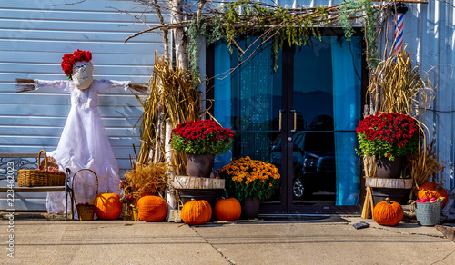 A fall harvest display- complete with pumpkins, scarecrow, autumn flowers and straw. © Mark Peugh