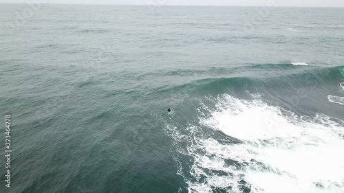 A Surfer in the water off the shore of Ericeira in Portugal waiting for a wave to catch. HD. photo