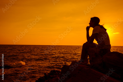 Silhouette women sitting alone on the rock. Mental health, PTSD and suicide prevention. Natural moment and back to nature for peace and serenity.