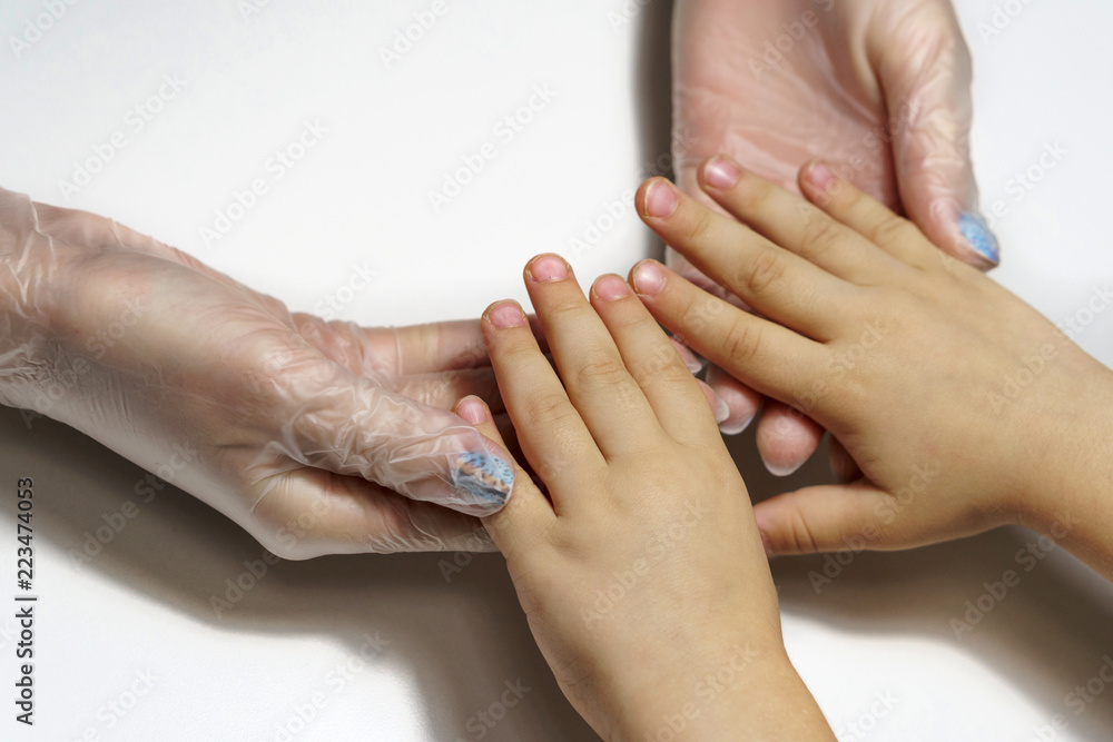 Professional manicure for child. Beautician holds child's hand. Shooting close-up. Professional manicure for child. Beautician holds child's hand. Shooting close-up.