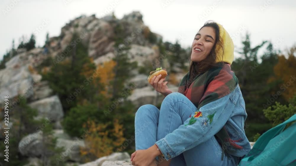 Girl eating hot dog on top of mountain. Girl eating hot dog on top of mountain.