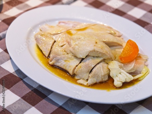 Chinese steamed chicken with sauce on a white plate on red checked Pattern tablecloth