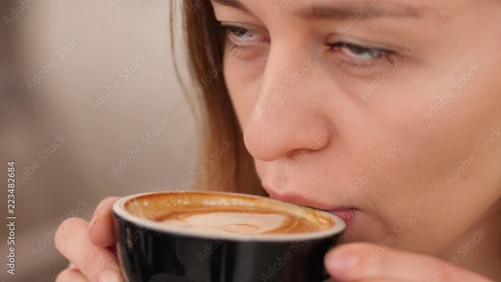 Closeup pretty young woman face drinking cup of coffee cappuccino in cafe Closeup pretty young woman face drinking cup of coffee cappuccino in cafe