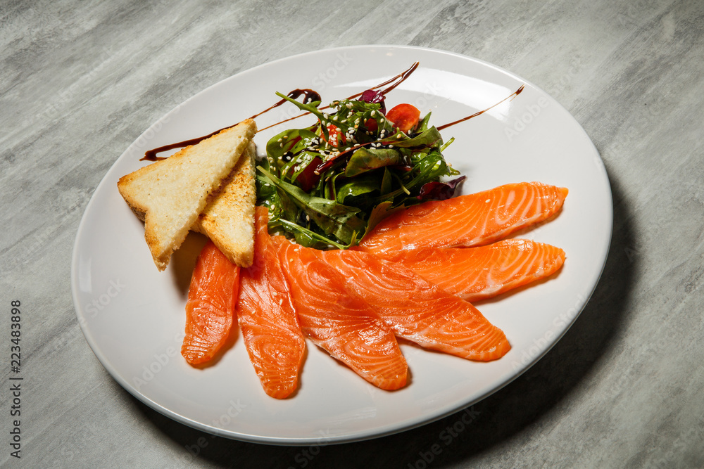 salmon slices served with rucola and tomato salad and toasted bread salmon slices served with rucola and tomato salad and toasted bread