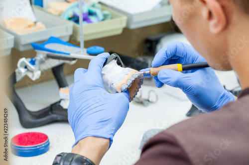 A dental technician dentist working with prostheses in a laboratory with wax on a jaw model