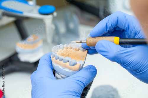 A dental technician dentist working with prostheses in a laboratory with wax on a jaw model