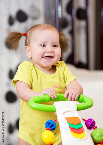 baby girl smiling while standing in walker