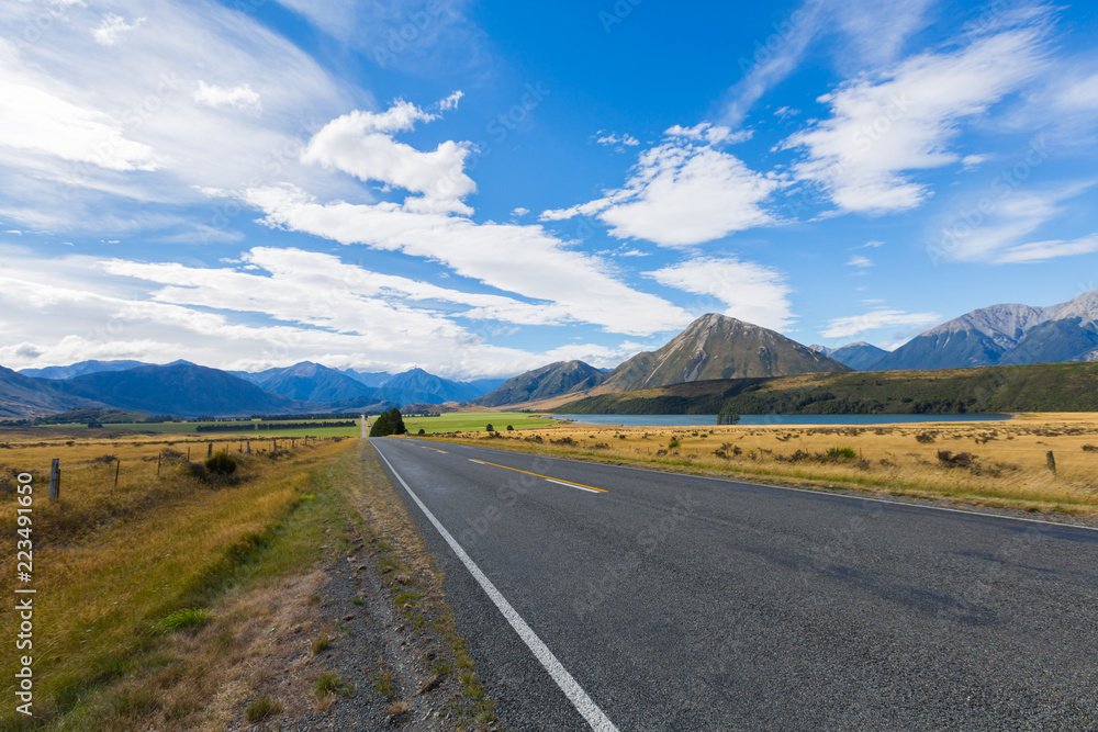 Car on the road trip,  Rural Scene of Asphalt Road with Meadow and Mountain Range, South Island, New Zealand