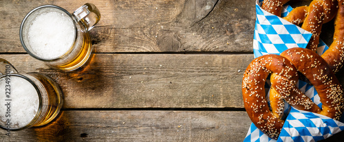 Foto Oktoberfest concept - pretzels and beer on rustic wood background, top view