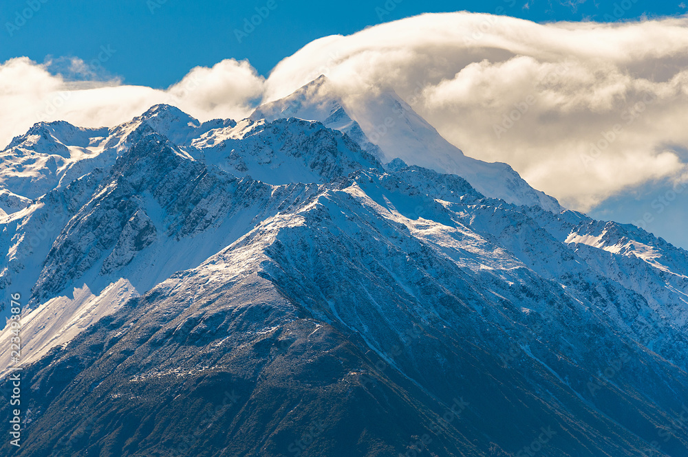 MOUNTAIN TOP COVERED WITH SNOW AND CLOUD. Large cloud passes over mountain covered with snow at Mount Cook, New Zealand. MOUNTAIN TOP COVERED WITH SNOW AND CLOUD. Large cloud passes over mountain covered with snow at Mount Cook, New Zealand.
