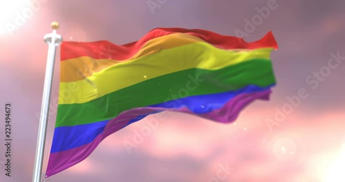 The rainbow flag, pride flag, LGBT pride flag or gay pride flag waving at wind at sunset, loop photo