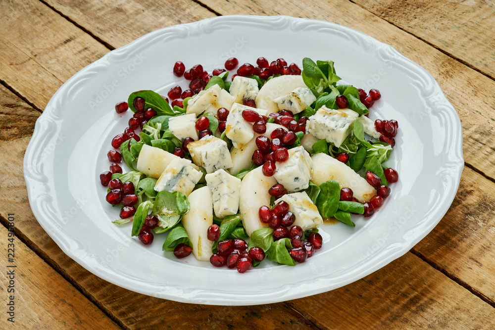 delicious salad of pear gorgonzola cheese and lettuce on a white plate on a wooden table