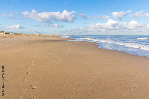 beautiful sandy beach with blue sky clouds, and footsteps forground