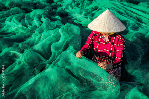 Young Vietnamese woman sitting repair the fish net in the morning,traditional fisherman.
