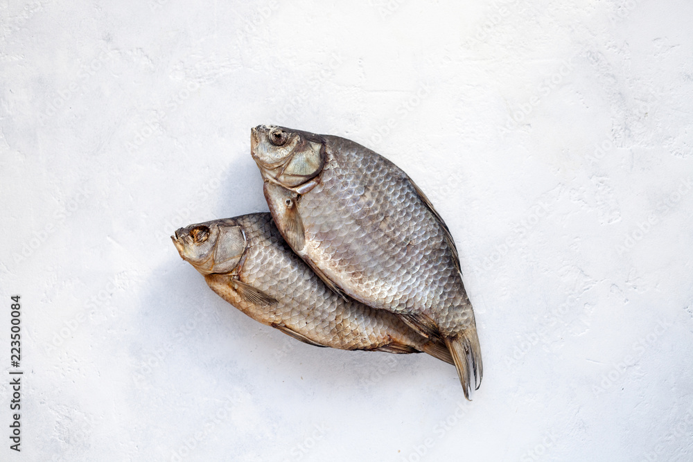 Two dried fish carp on a white concrete background