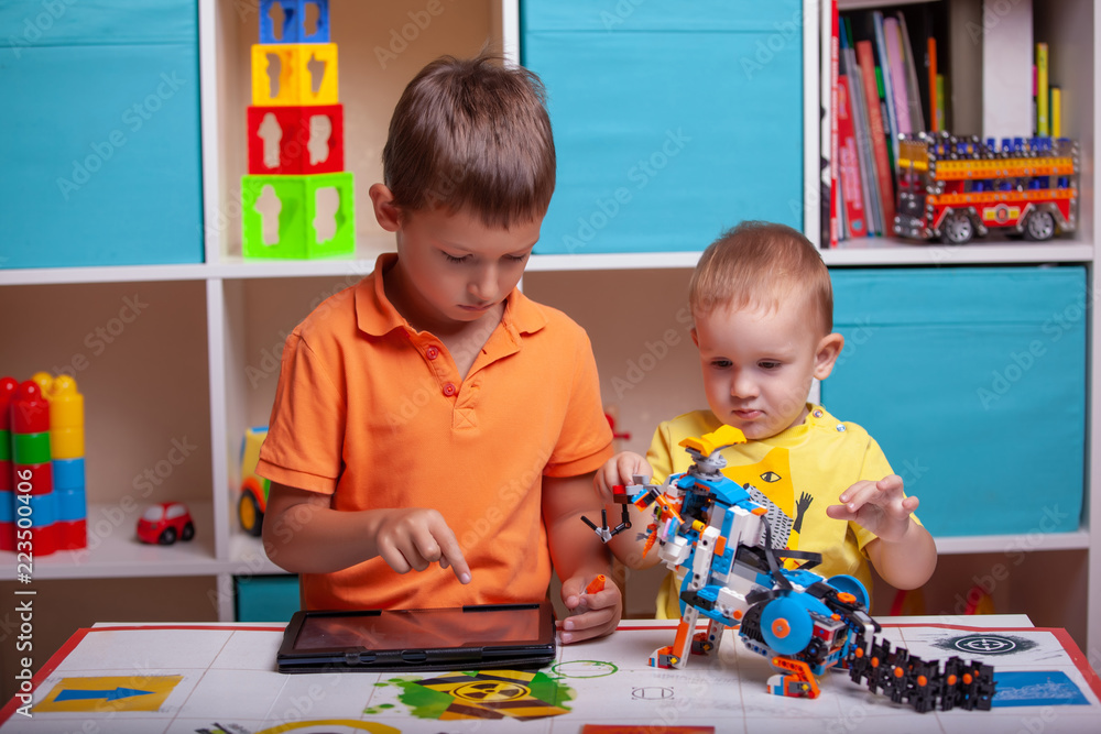 Fototapeta premium Two boys сhild collects robot from the plastics details