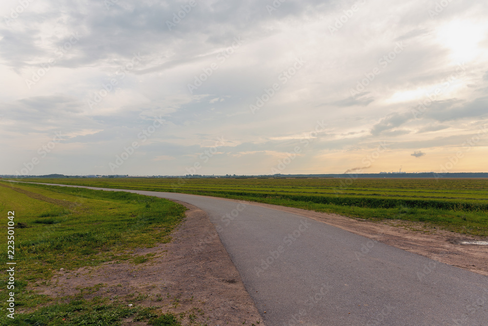 asphalt road in the field with  mown grass in the northern part of Russia.
