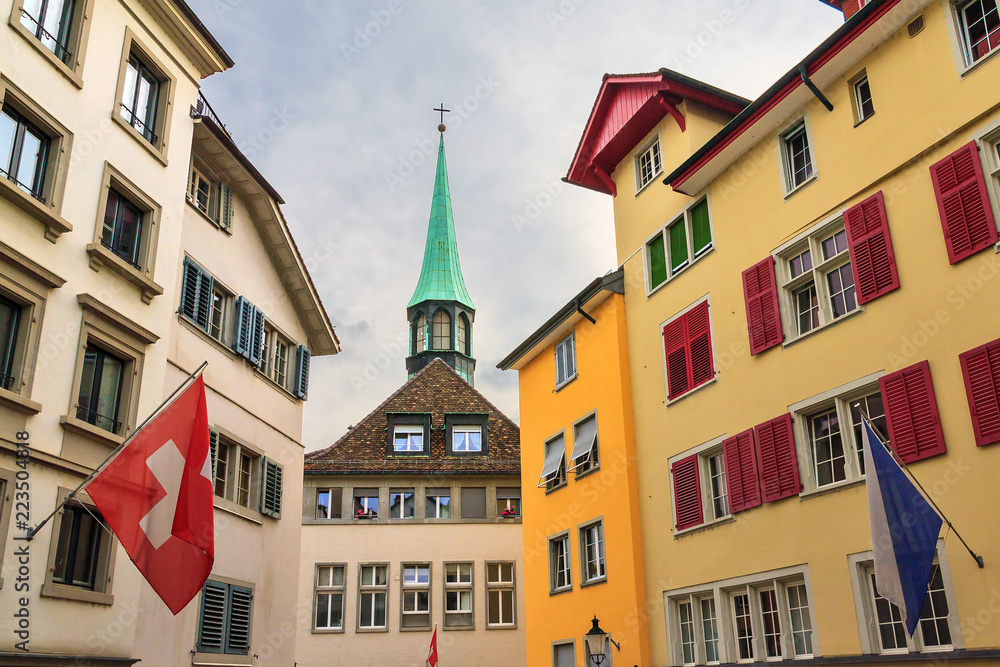 Fototapeta premium Beautiful cityscape of the colorful houses with flags and green church tower in Zurich, Switzerland 