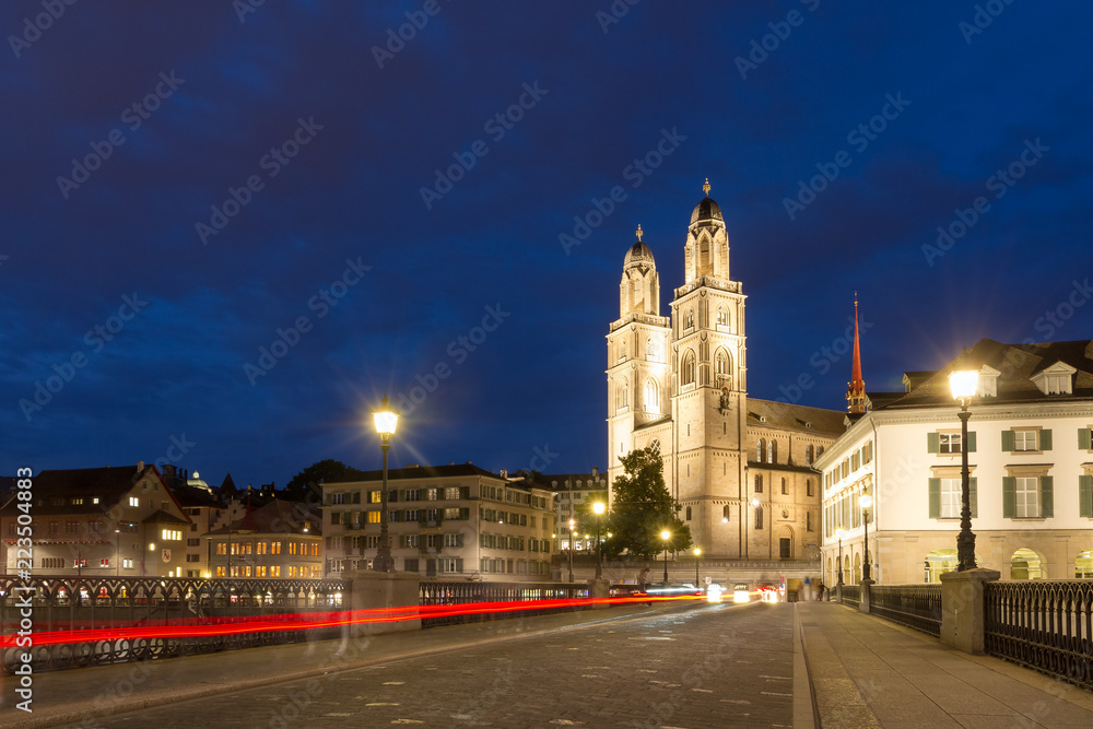 Beautiful cityscape of Zurich, Switzerland, with the Grossmünster Protestant church, seen from the bridge over the river Limmat at night in summer