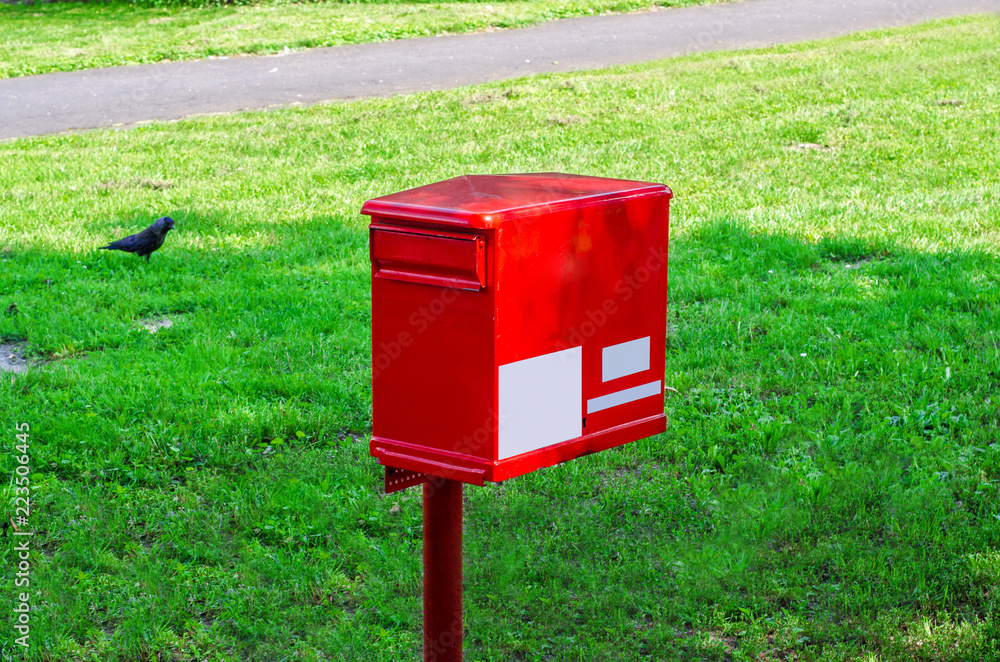 Mailbox red color on a column on a green background Mailbox red color on a column on a green background