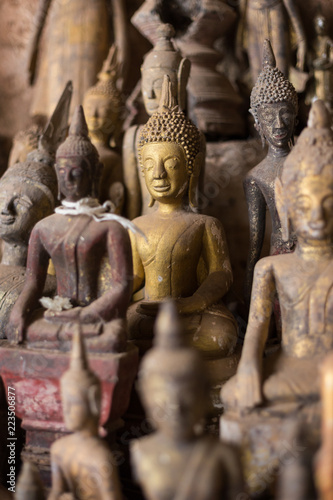 Close-up of many old and faded, golden and wooden Buddha statues inside the Tham Ting Cave at the famous Pak Ou Caves near Luang Prabang in Laos.