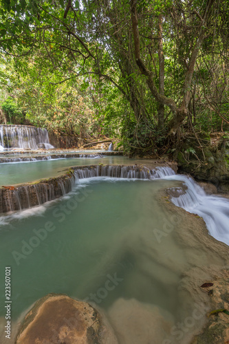 Beautiful view of a small waterfall and cascades at the Tat Kuang Si Waterfalls near Luang Prabang in Laos on a sunny day.