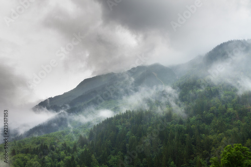 Clouds and fog in the green forest mountains in the Rhone valley near Brig and Sion in Switzerland, on a summer morning