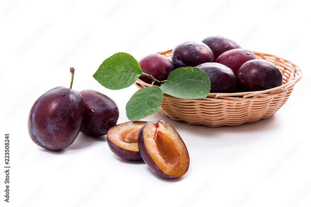 Yellow wooden basket with ripe plums, whole and half ripe plums isolated on a white background.. Yellow wooden basket with ripe plums, whole and half ripe plums isolated on a white background..