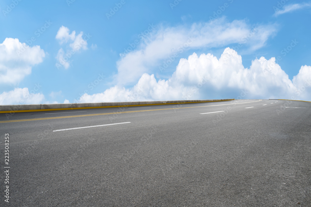 Fototapeta premium Road pavement under blue sky and white clouds