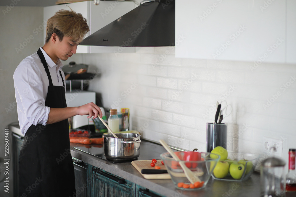 Asian cook in the kitchen prepares food in a cook suit Asian cook in the kitchen prepares food in a cook suit