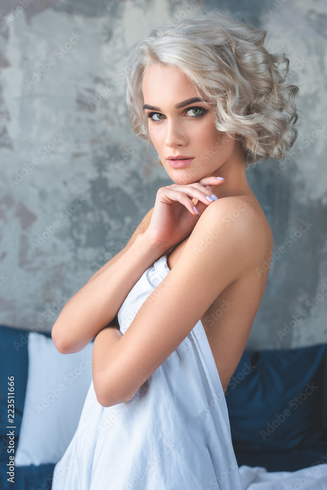 attractive naked young woman covering her body with white cloth and looking at camera attractive naked young woman covering her body with white cloth and looking at camera