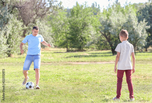Little boy with his dad playing football outdoors