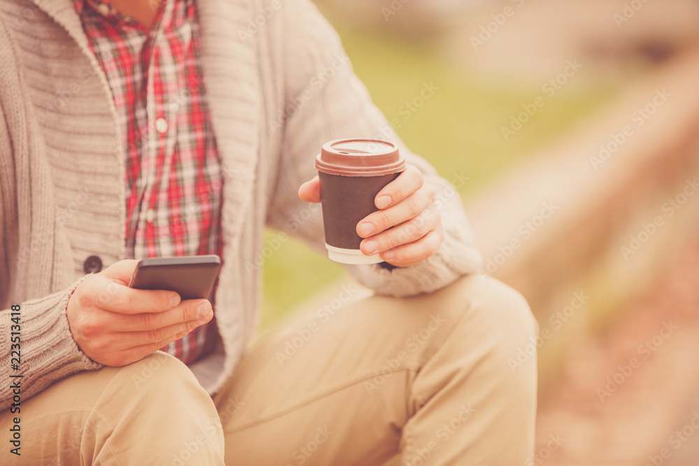 Attractive man using cellphone and drinking coffee outdoors. Attractive man using cellphone and drinking coffee outdoors.