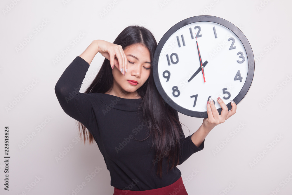 Sleepy young Asian woman with a clock in the morning. Sleepy young Asian woman with a clock in the morning.
