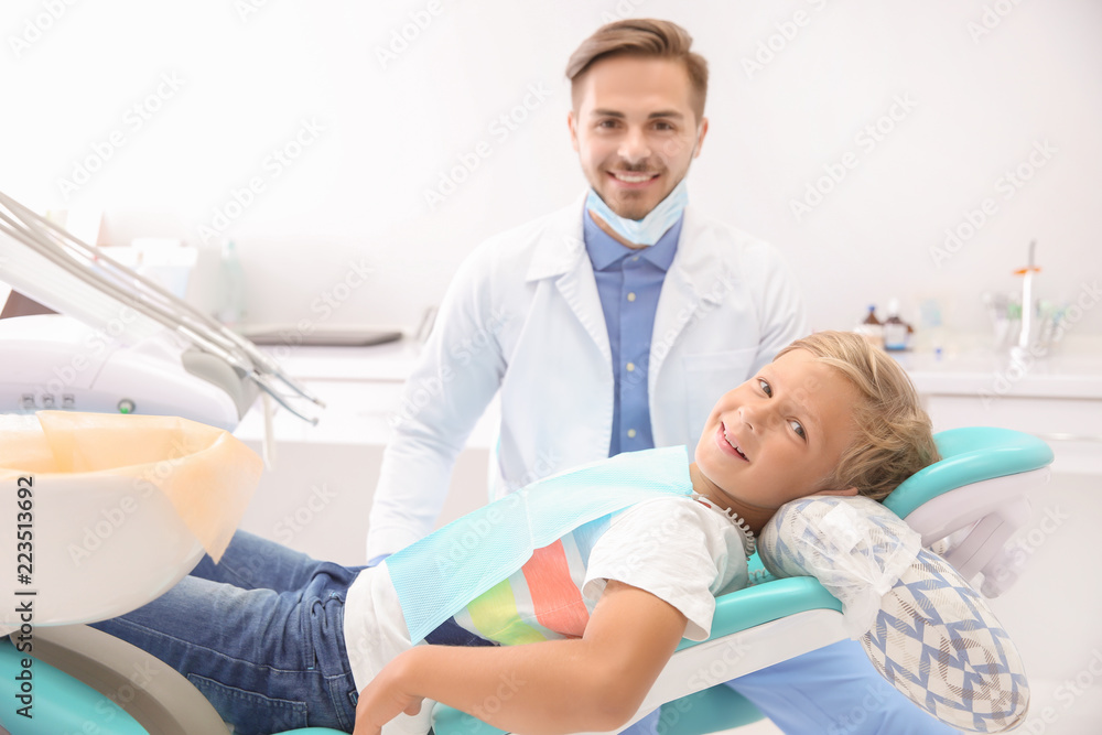 Fototapeta premium Dentist examining little boy's teeth in clinic