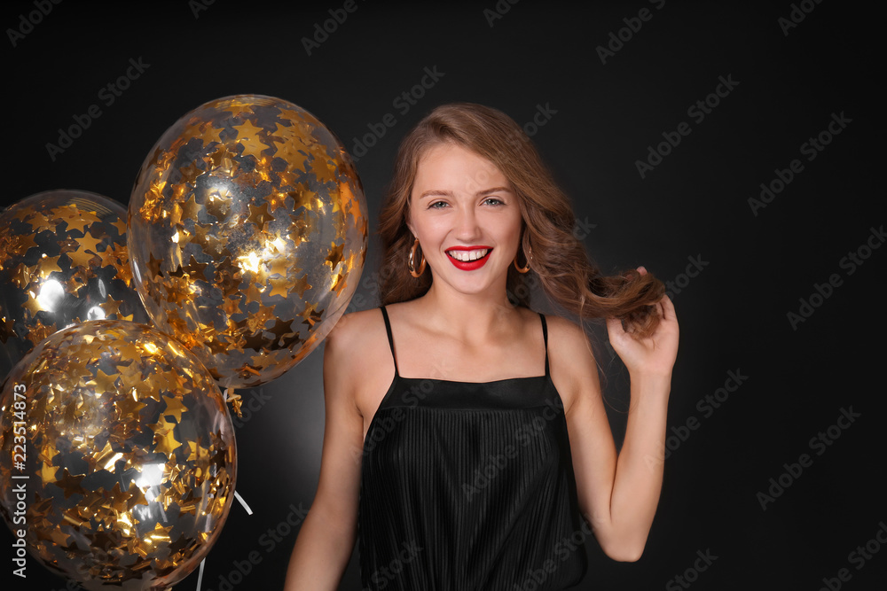 Naklejka premium Beautiful young woman with balloons on dark background