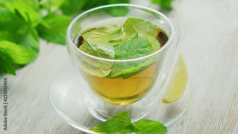 From above view of glass cup of green tea with leaves of mint and slice of lemon placed on saucer on wooden background From above view of glass cup of green tea with leaves of mint and slice of lemon placed on saucer on wooden background