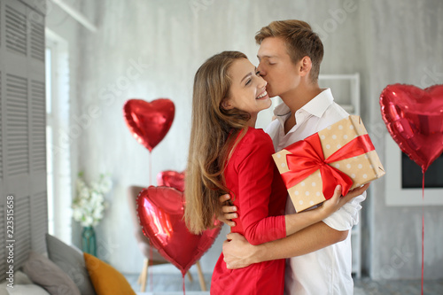 Quadro su tela Young couple with gift box hugging at home