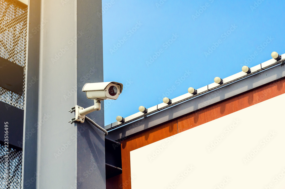 Surveillance camera is installed on a gray beam, parking a supermarket Surveillance camera is installed on a gray beam, parking a supermarket