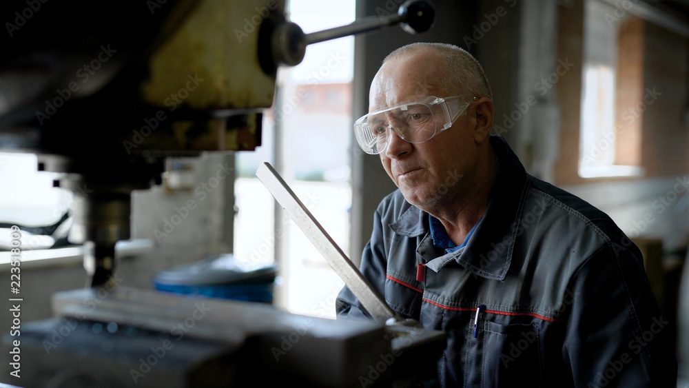 Close-up shot of an old, professional plant worker working at the standing drill machine oil up. Close-up shot of an old, professional plant worker working at the standing drill machine oil up.